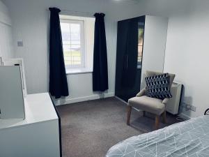 a bedroom with a bed and a chair and a window at Ellary Cottage in Lochgilphead