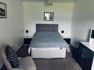 a bedroom with a bed and a couch and a chair at Ellary Cottage in Lochgilphead