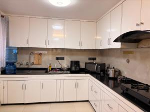 a kitchen with white cabinets and a black counter top at Fu Shang Villa in Kathmandu