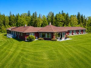 a red house with a large green yard at Baddeck Inn in Baddeck