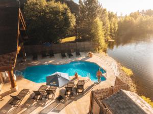 a man standing next to a swimming pool next to a lake at Auberge du Lac Taureau et Condos in Saint-Michel-des-Saints