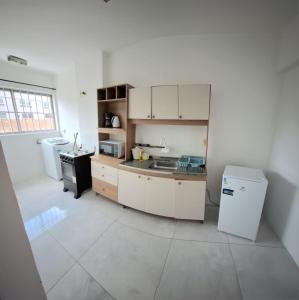 a kitchen with white cabinets and a sink and a refrigerator at Loft central, cozinha e sala in Joinville +7 photos
