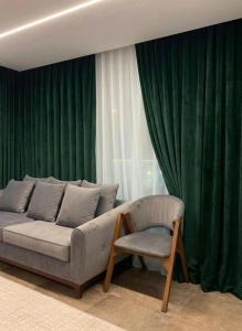 a couch and a chair in a room with green curtains at Blue Pyramids Eyes Hotel in Cairo +48 photos