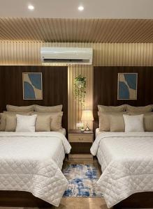 a bedroom with two beds and a table with a lamp at Blue Pyramids Eyes Hotel in Cairo