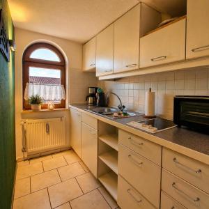a kitchen with white cabinets and a sink and a window at Ferienwohnung Weber Alpenveilchen in Lechbruck
