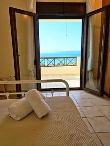 a bed in a room with a view of the ocean at Vista Mare Aegina in Kipséli