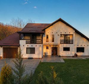 a large white house with a large yard at Casa Liniștea Pădurii in Gura Văii