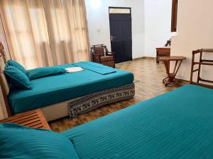two beds in a hotel room with blue sheets at Green Senz - Tourist Board Approved Hotel & Hostel - Sigiriya in Sigiriya