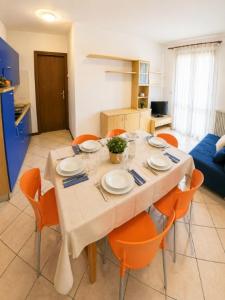 a dining room table with orange chairs in a kitchen at Residence Pineta - Agenzia Cocal in Caorle +6 photos