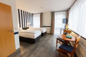 a hotel room with two beds and a table at Hotel DH VEC in Vechta +17 photos