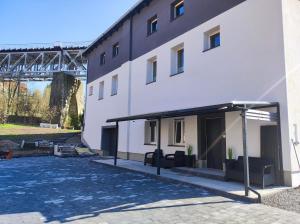 a large white building with a canopy next to a bridge at Apartamenty Pod Wiaduktem in Ober Wüstegiersdorf