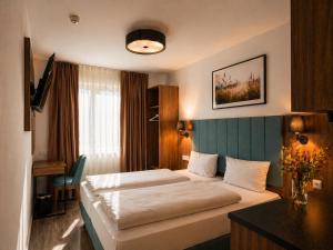 a hotel room with a bed and a desk at Lillys Hotel München in Unterschleißheim +31 photos