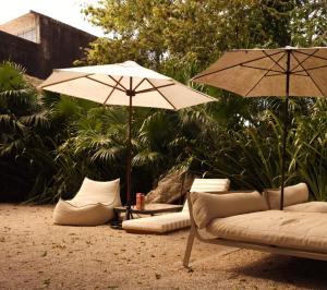 two umbrellas and a couch and chairs in the sand at Artos Hostel in Mérida