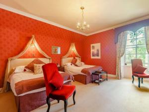 a bedroom with two beds and a red wall at 5 Bed in Melrose oc-89348 in Newtown Saint Boswells