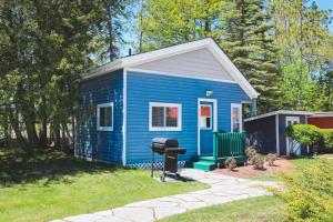 a blue tiny house with a grill in a yard at Lighthouse at Evergreen Resort in WB in Wasaga Beach