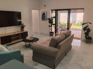 a living room with a couch and a flat screen tv at Mtunzini South Cottage in Mtunzini