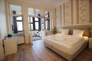 a bedroom with a bed with white sheets and windows at Villa Pippingsburg am Strand in Ahlbeck
