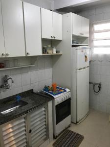 una pequeña cocina con fogones y nevera. en Apartamento José Menino, en Santos