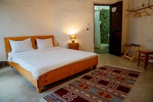 a bedroom with a large bed and a table at Cob Village - Casute din lut, self check-in, experienta in natura in Berca