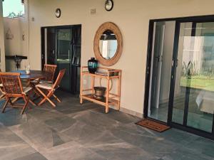a dining room with a table and chairs and a mirror at Mtunzini South Cottage in Mtunzini