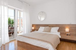 a white bedroom with a large bed and a balcony at Apartments Tihi III in Vodice +91 photos