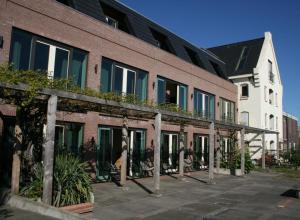 a brick building with a balcony with plants on it at Hotel Noudus in Delfstrahuizen