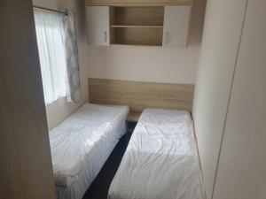 a small room with two beds and a window at Caravan 325 in Lowestoft