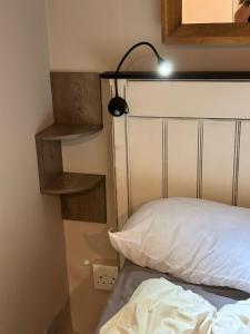 a bed with a white pillow and a light above it at Meerlust Cottage in Cape Town