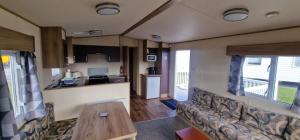 a living room with a couch and a table in a caravan at Ty Mawr Summerbreeze in Kinmel Bay
