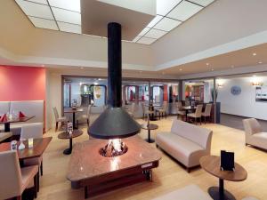 a lobby with a fireplace and tables and chairs at ibis Styles Louvain-la-Neuve Hotel and Events in Louvain-la-Neuve