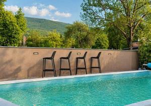 three bar stools sitting on a wall next to a swimming pool at Holiday home Melani - with private heated pool and sauna in Sinac