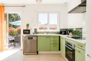 a kitchen with green and white cabinets and appliances at Villa Santa - Piscine - Wifi - Proche Ventoux - idéal Cyclistes in Mormoiron