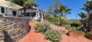 a house with a garden with flowers and a stone wall at Oasis Villa - Sea View Pool, Sanremo in Sanremo