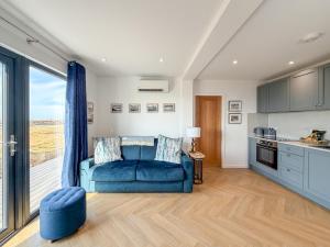 a living room with a blue couch and a kitchen at Bothan By The Bay, Benbecula in Grimsay