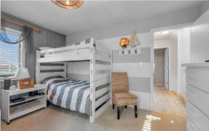 a bedroom with a white bunk bed and a chair at Isle be sea'n you in Rodanthe