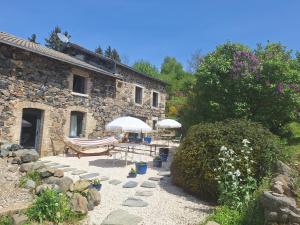 a stone house with two umbrellas and a patio at Lou Montadou in Yssingeaux