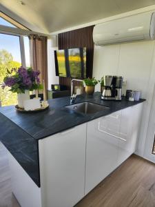 a kitchen with white cabinets and a black counter top at Bei Herze - Tiny Wohnen im Odenwald in Bad König