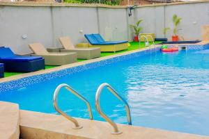 a swimming pool with chairs and a pool noodle at Diplomats Enclave Suites in Jikoyi