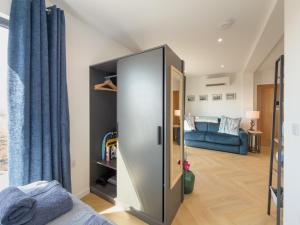 a room with a large glass door with a blue couch at Bothan By The Bay, Benbecula in Grimsay