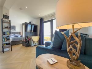 a living room with a blue couch and a table with a lamp at Bothan By The Bay, Benbecula in Grimsay
