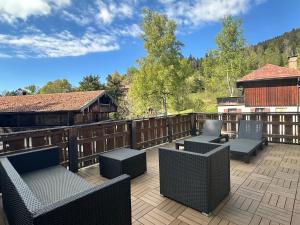 a patio with chairs and tables on a deck at Design-Apartment am Wildbach mit Bergblick & direktem Zugang zur Natur in Fischbachau