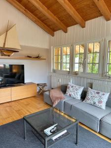 a living room with a couch and a tv at Design-Apartment am Wildbach mit Bergblick & direktem Zugang zur Natur in Fischbachau