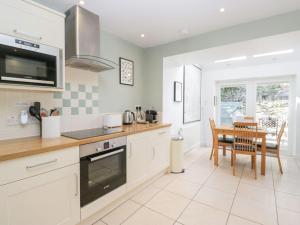 a kitchen with white cabinets and a table and chairs at Rothay Cottage in Ambleside