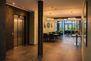 a lobby with a dining room with tables and chairs at Lillys Hotel München in Unterschleißheim