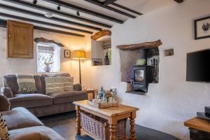a living room with a couch and a tv at Potter's Wheel, by the lake in High Nibthwaite
