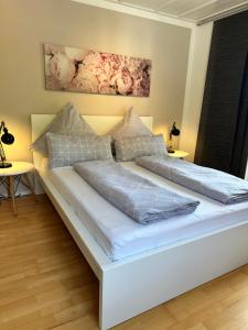 a large white bed in a room with two tables at Design-Apartment am Wildbach mit Bergblick & direktem Zugang zur Natur in Fischbachau