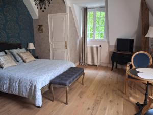 a bedroom with a bed and a desk and a television at Le Mesnil Landon in Lingèvres