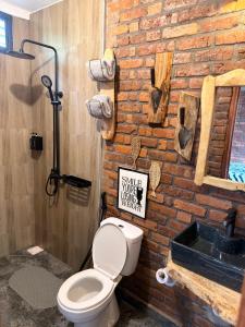 a bathroom with a toilet and a brick wall at Villa Rosa in Moshi