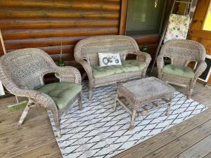 three wicker chairs and a stool on a porch at Connie's Little House in Elmira