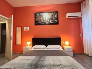 a bedroom with an orange wall with a bed and two lamps at Adriatic Room 50 m dalla stazione Ferroviaria di Ciampino e dalla navetta aeroportuale in Ciampino